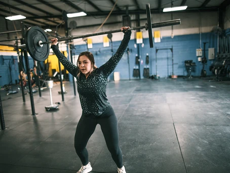 A woman lifting a barbell in a gym.