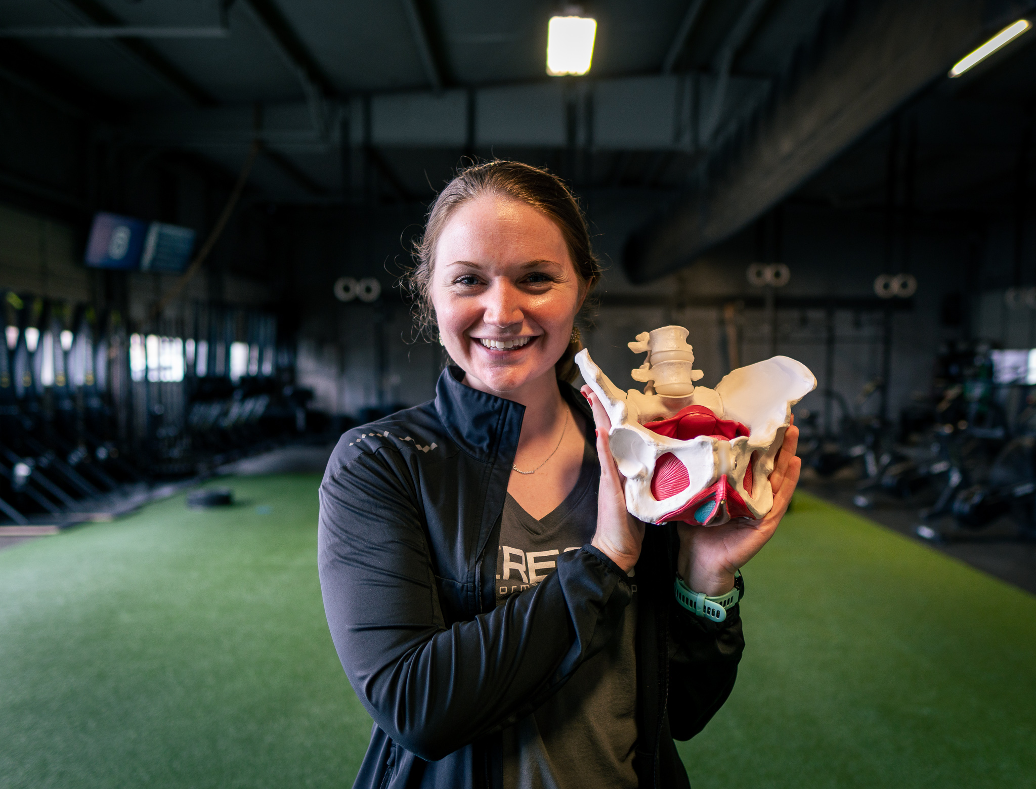 A woman holding a bone model in a gym.