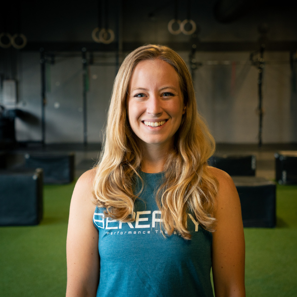 A woman in a blue shirt standing in front of a gym.